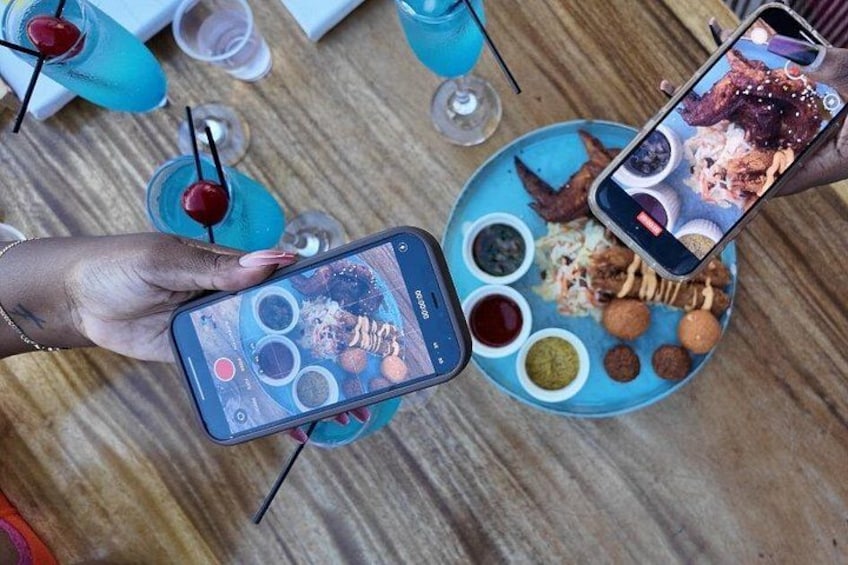En person som håller en smartphone, med en bricka med mat i bakgrunden. 3