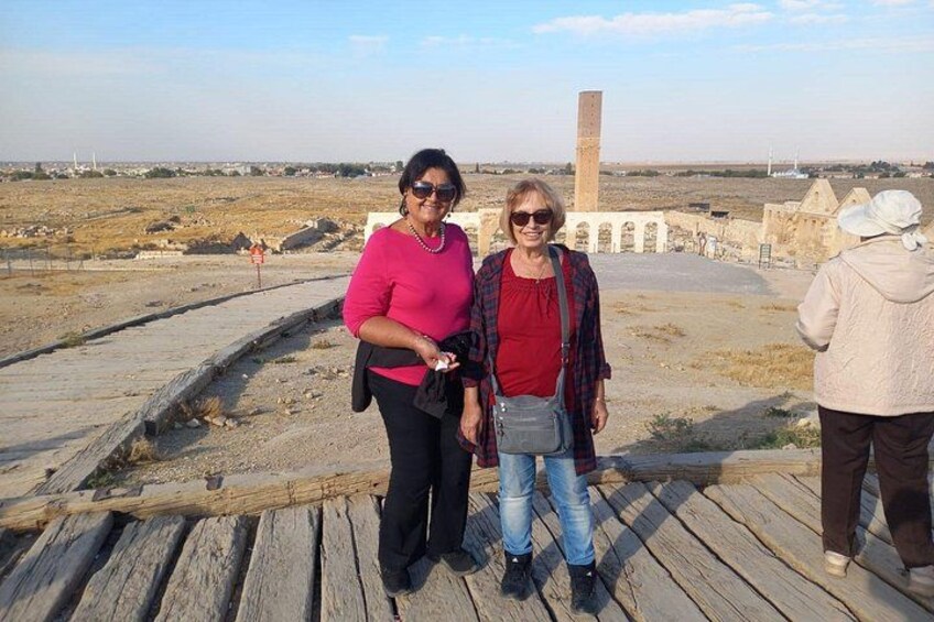 Two people standing on a wooden platform with a historical site in the background. 5