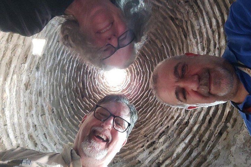 Three people inside a circular, textured structure with a light source at the center. 3