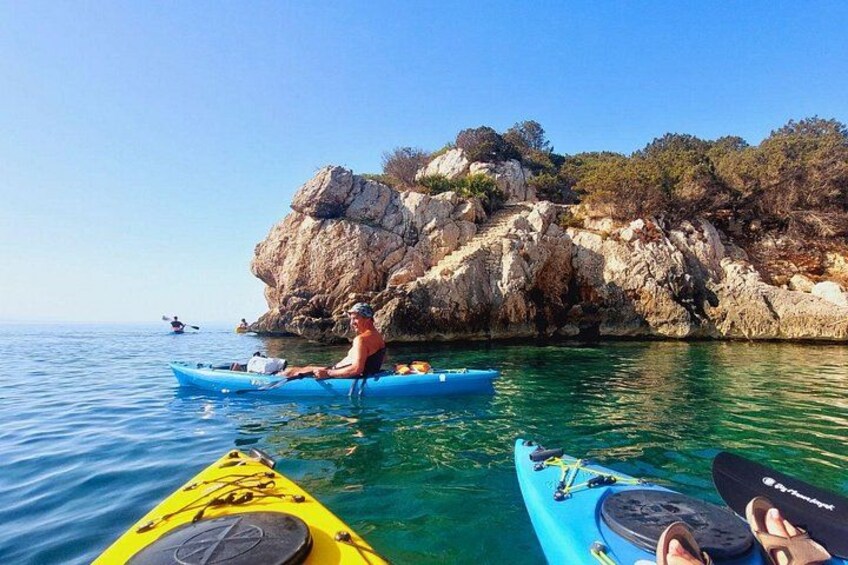 A person kayaking on clear water with rocky cliffs in the background. 1