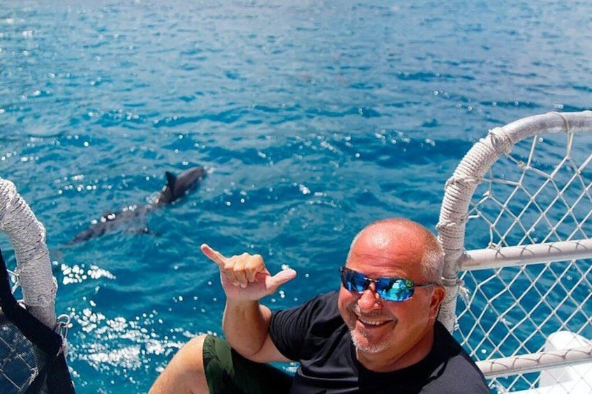 En person på en båd med en delfin i vandet. 4