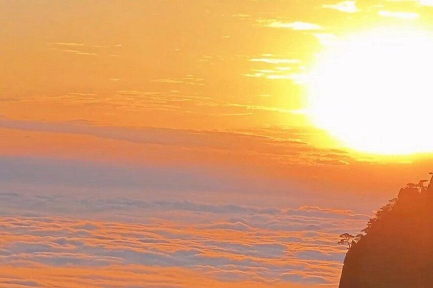 A sunset over a mountainous landscape with clouds below. 2