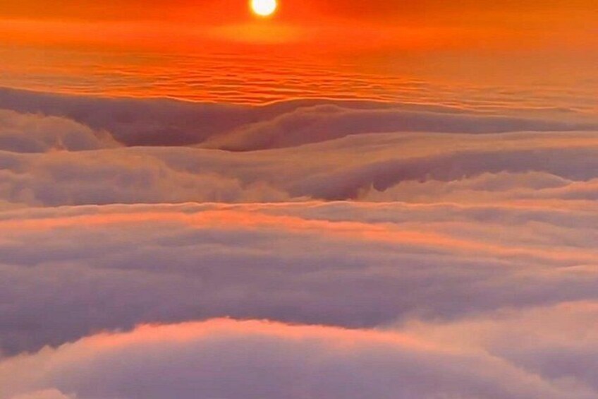A sunset over a sea of clouds with a visible sun. 5