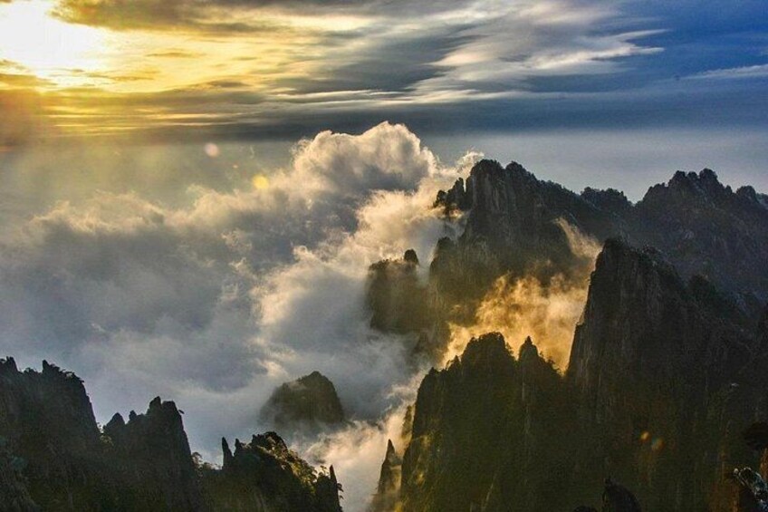 A mountainous landscape with rugged peaks and clouds below. 1