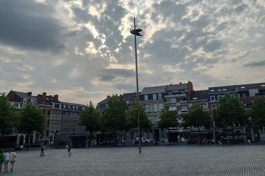 Une place pavée, bordée de bâtiments historiques, avec un lampadaire et un ciel nuageux. 3