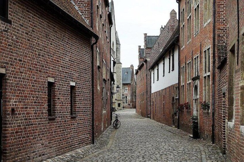 Une rue pavée bordée d’immeubles en briques rouges, un vélo et un ciel dégagé. 4