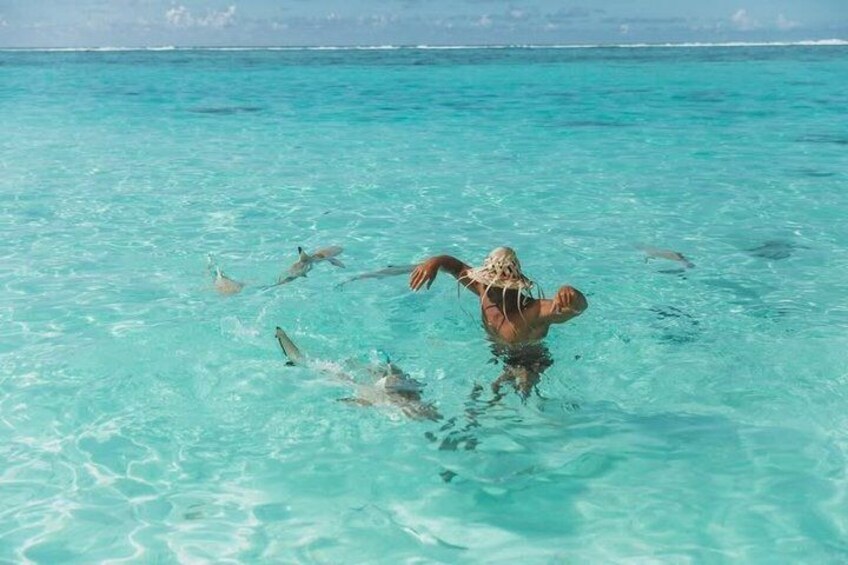 A person swimming in clear turquoise water with stingrays. 4