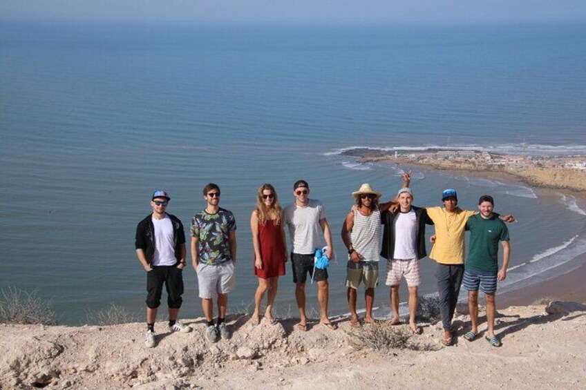 A group of people standing on a sandy beach with the ocean in the background. 3