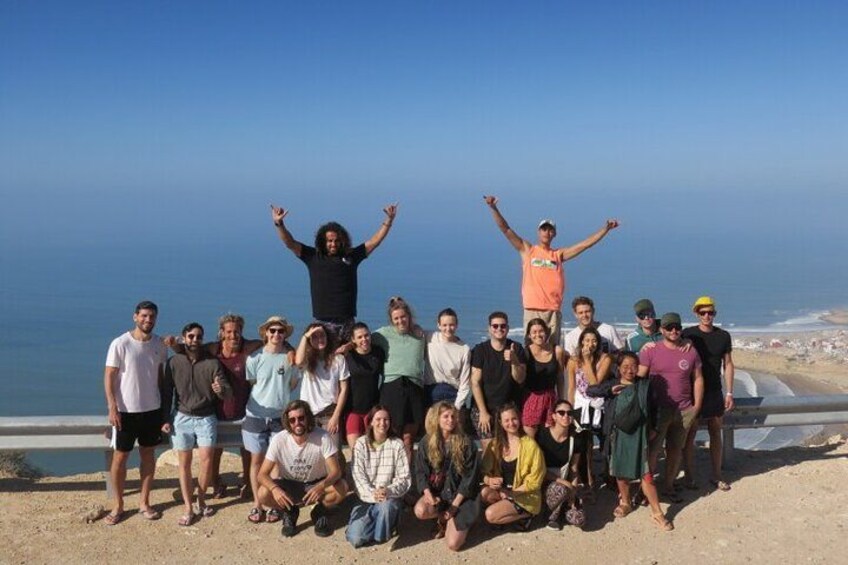 A group of people posing on a beach with the ocean in the background. 4