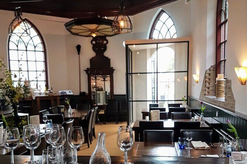 A restaurant interior with high wooden ceilings, arched windows, and a fireplace. 2