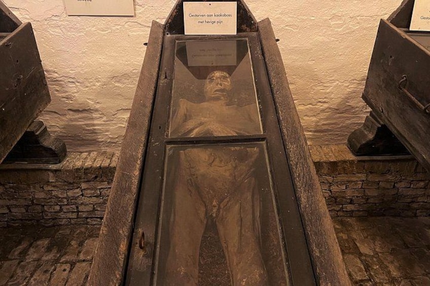 A historical exhibit with a wooden coffin and a plaque. 4
