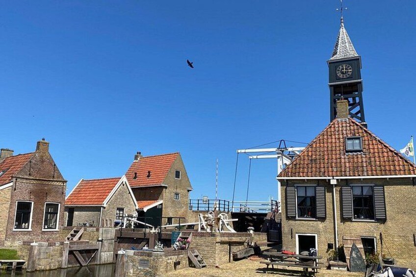 A coastal town with traditional buildings, a church tower, and a crane in the background. 5