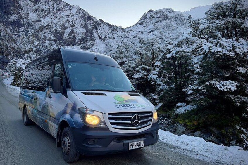 A CHEROKEE branded van driving on a snow-covered mountain road. 3
