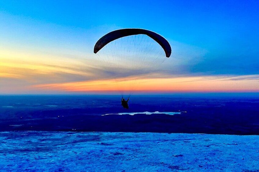 A person paragliding over a vast landscape during sunset. 3