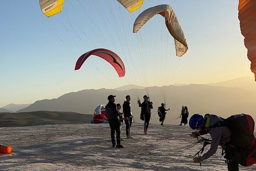 A group of people preparing for paragliding with parachutes on a snowy landscape. 4