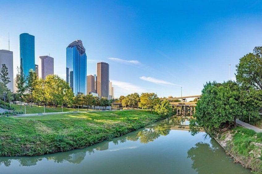 A cityscape with modern skyscrapers, a calm river, and green park areas. 3