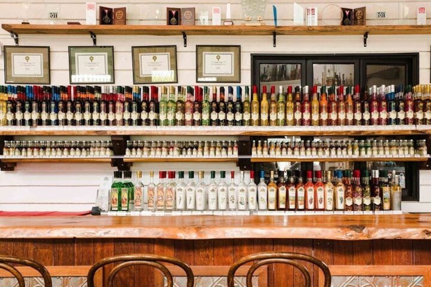 A bar with shelves of liquor bottles and framed certificates on the wall. 2