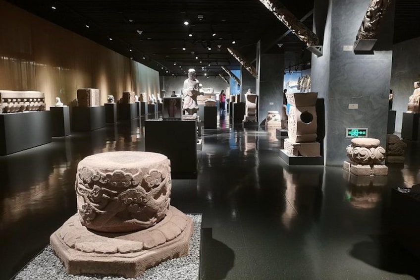 A museum interior with stone sculptures on display. 3