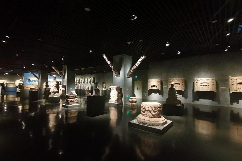An indoor museum with stone sculptures and artifacts on display. 2