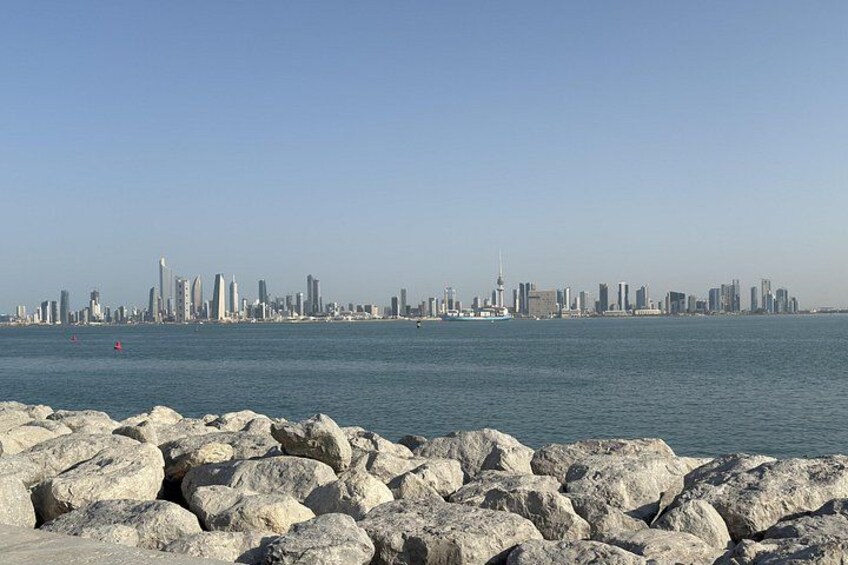 A coastal city skyline with prominent buildings and a rocky shoreline. 2