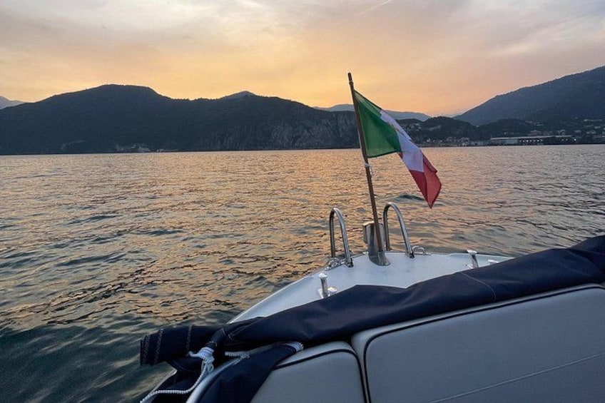 A boat with an Italian flag, calm water, and mountains in the background. 3