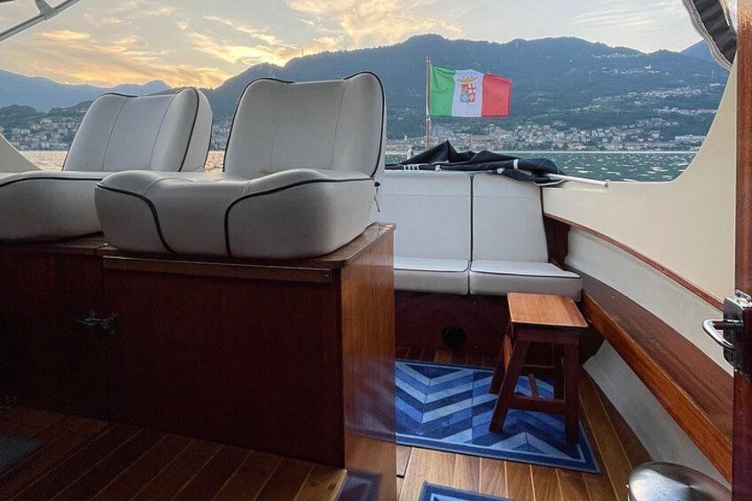 A boat's deck with seating, a flag, and a view of a city and mountains. 5