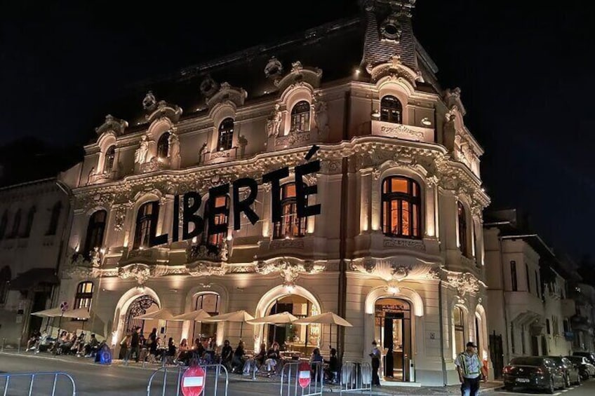 A historic building with ornate architecture and the name "LIBERTE" illuminated on the facade. 4