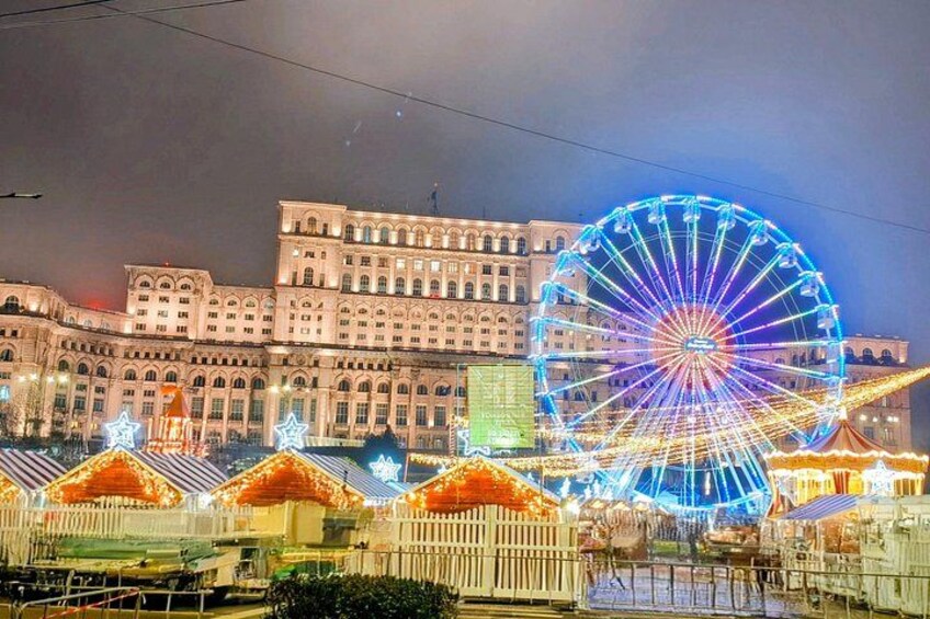 A large Ferris wheel, a historic building, and a fenced area with tents. 2