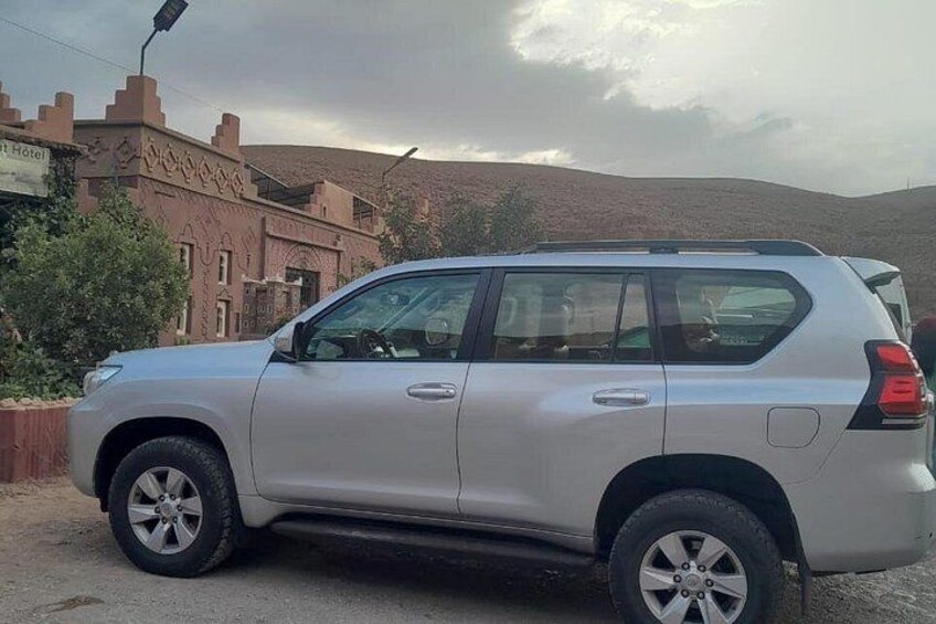 Un SUV plateado estacionado en una calle con un edificio identificado como 'Hotel' al fondo. 2