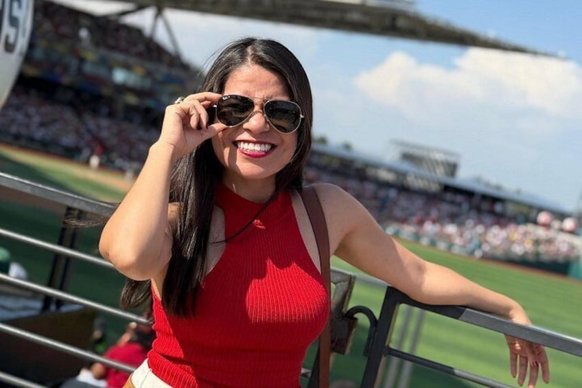 Una persona con remera roja en un estadio deportivo, con césped verde y espectadores al fondo. 1