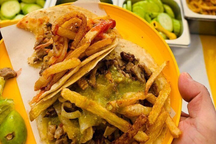 Un taco con carne, queso y cebolla sobre un plato amarillo. 3