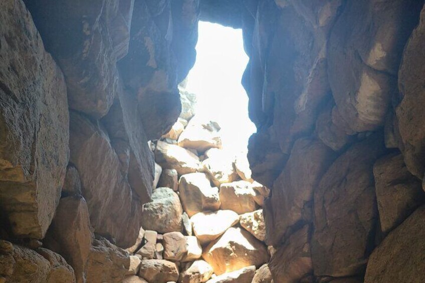 A narrow canyon with large boulders and a bright light at the end. 5