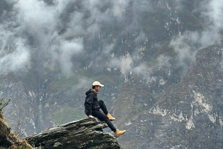 A person sitting on a rock in a mountainous area. 5