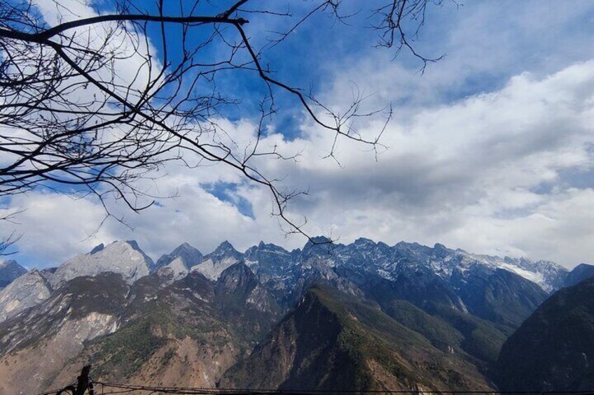 A mountain range with snow-capped peaks under a partly cloudy sky. 3