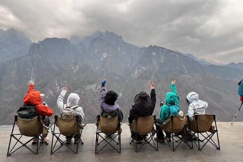 People sitting on chairs facing a mountain range. 4