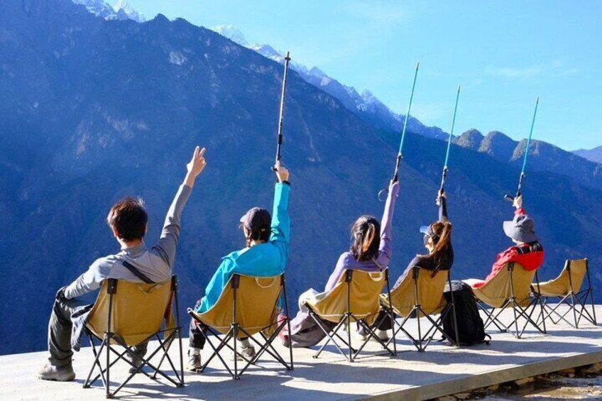 People sitting on chairs with poles, overlooking a mountainous landscape. 1