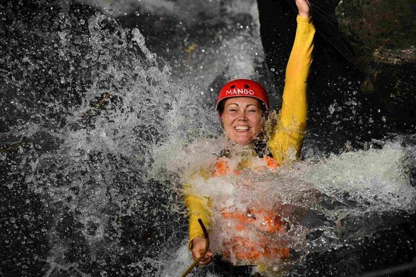 A person in a yellow jacket and red helmet, partially submerged in water with splashes around. 5