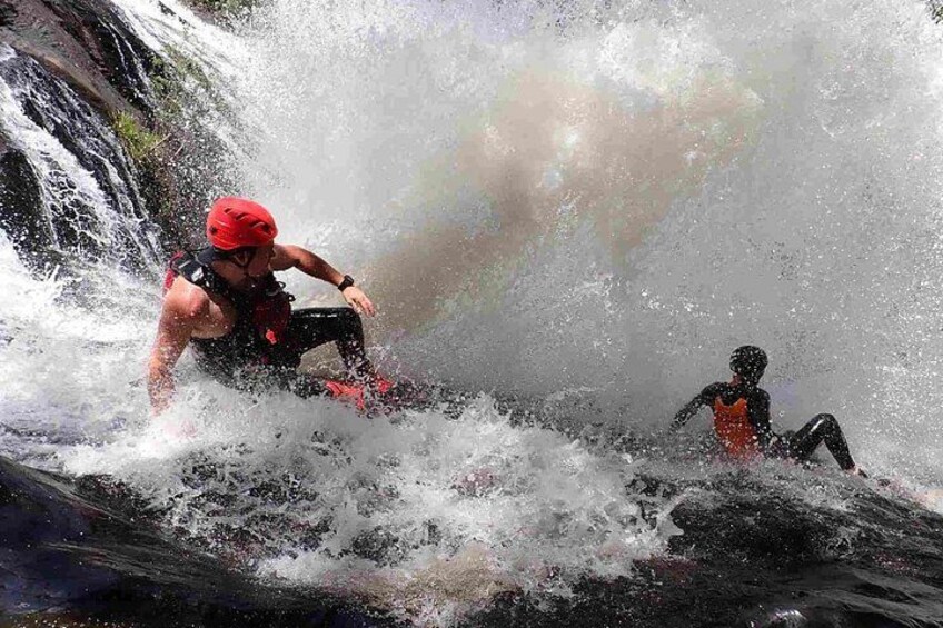 A person in a red helmet and life jacket riding a red surfboard on a wave. 2