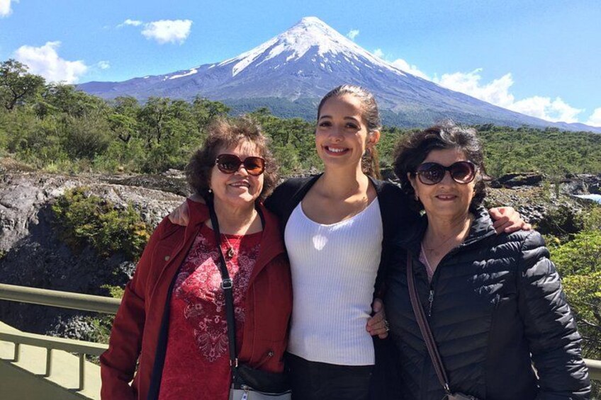 Three people standing in front of a mountain with a snow-capped peak. 4
