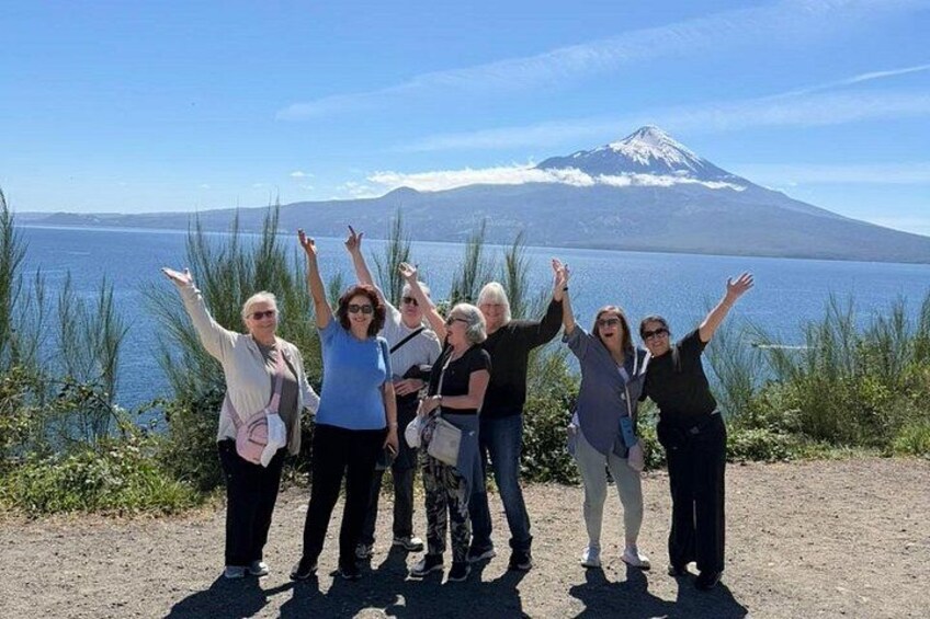 A group of people standing by a lake with a mountain in the background. 1