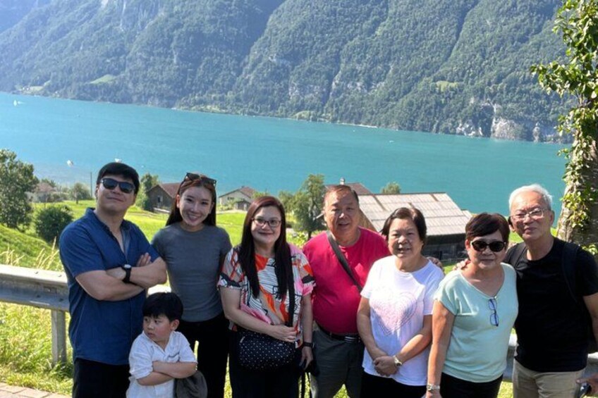 Un grupo de personas de pie junto a un lago con montañas al fondo. 3