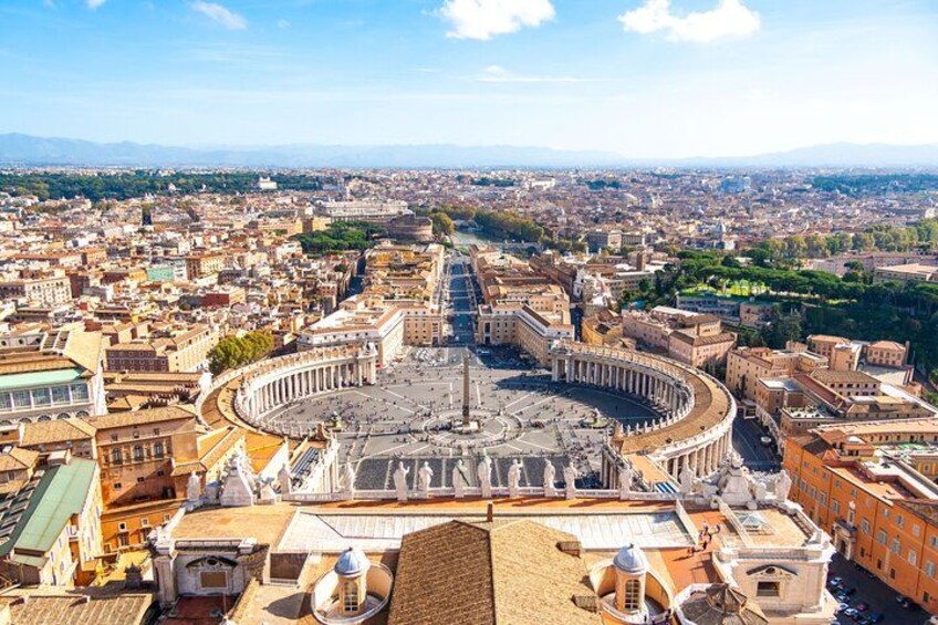 A panoramic view of a historic city center with a prominent circular plaza, a large cathedral, and surrounding urban buildings. 3