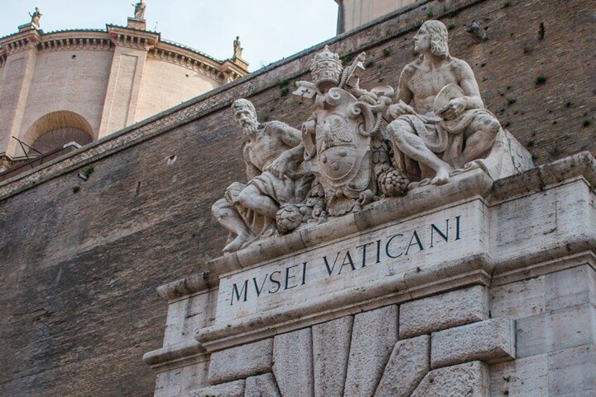 A stone relief with the inscription 'MVSEI VATICANI' on a building facade. 5