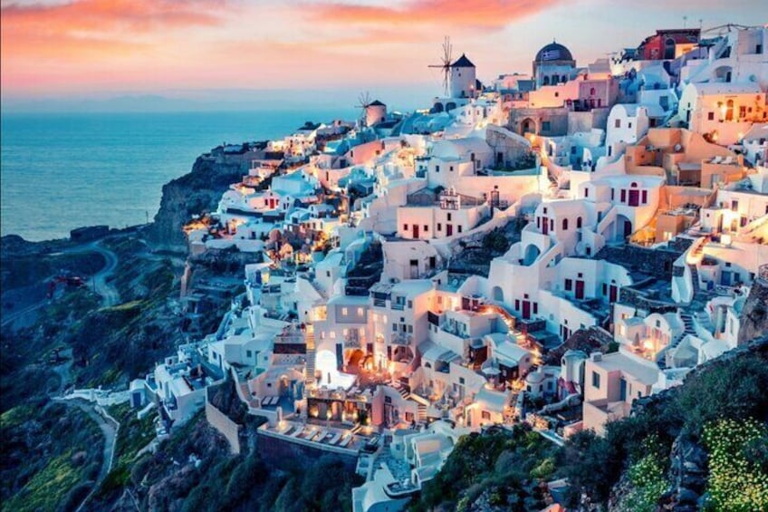 A coastal village with white buildings, a windmill, and a sunset. 3