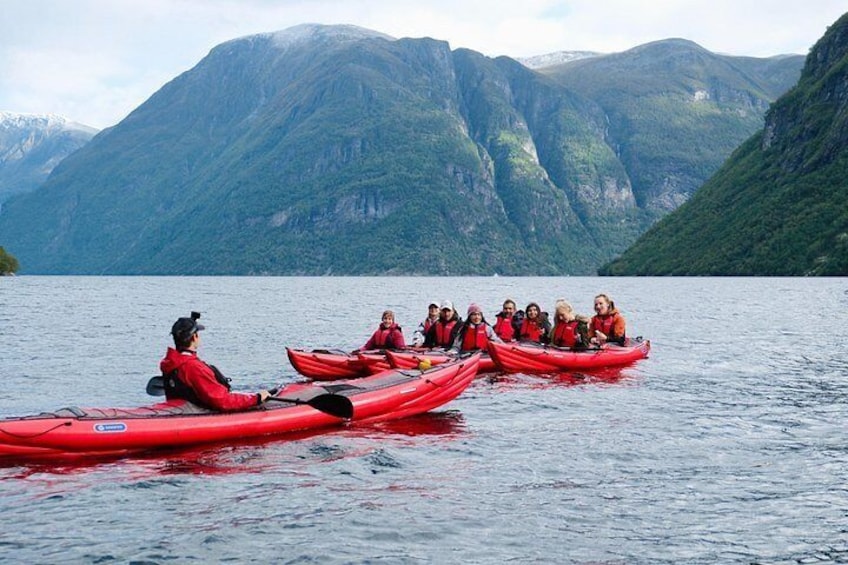 Un grupo de personas haciendo kayak en un lago tranquilo rodeado de montañas. 1