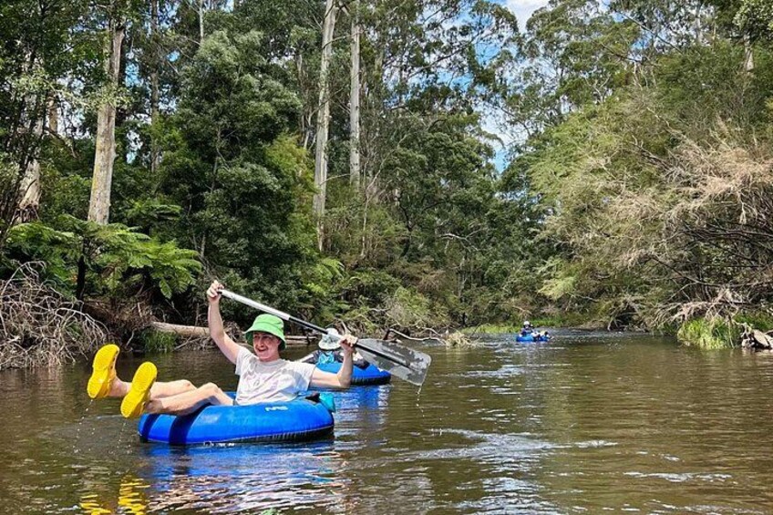 Two people in blue inflatable rafts on a river surrounded by trees. 3
