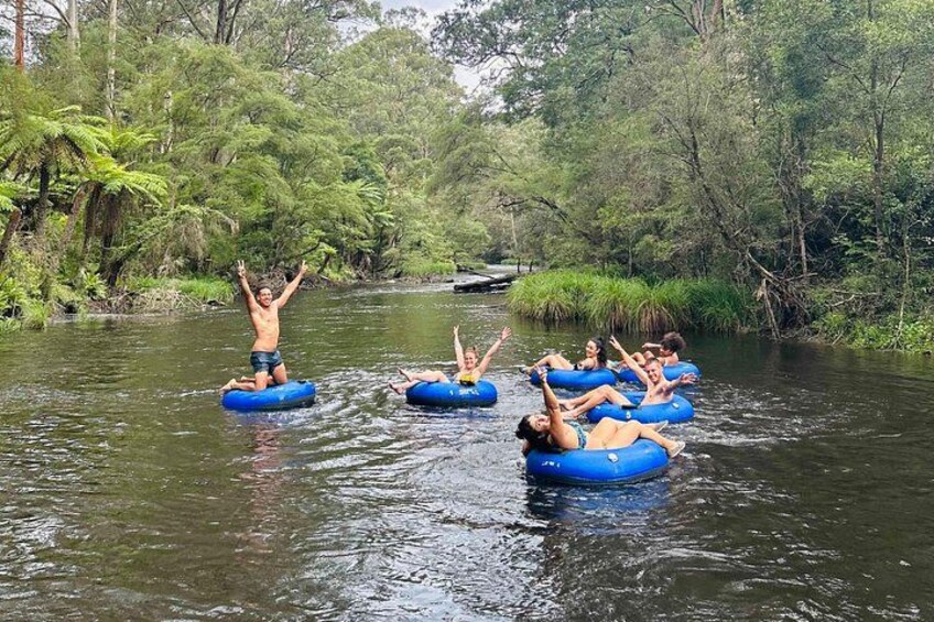 People floating on blue rafts in a river surrounded by dense greenery. 1