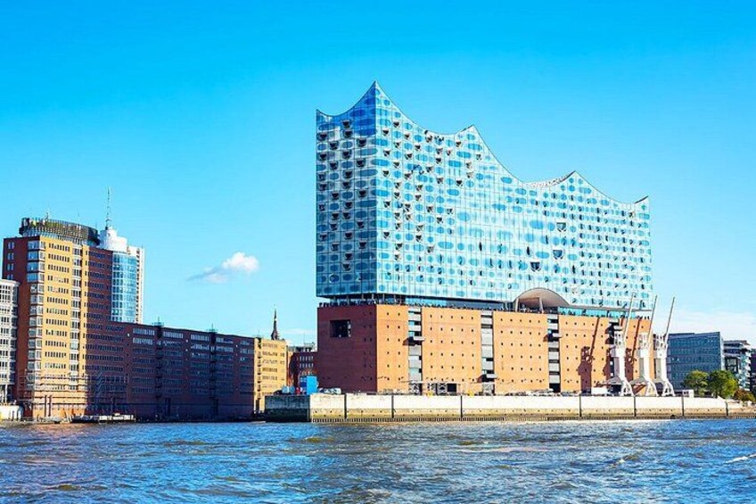A modern building with a unique blue facade, a river in the foreground, and other surrounding buildings. 5
