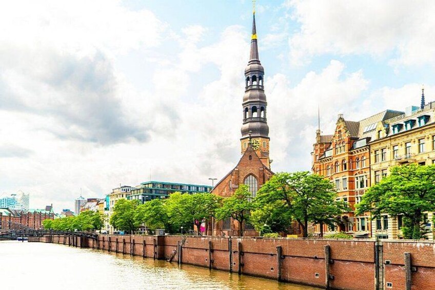 A river with a bridge, a tall church with a spire, and historic buildings along the riverbank. 3