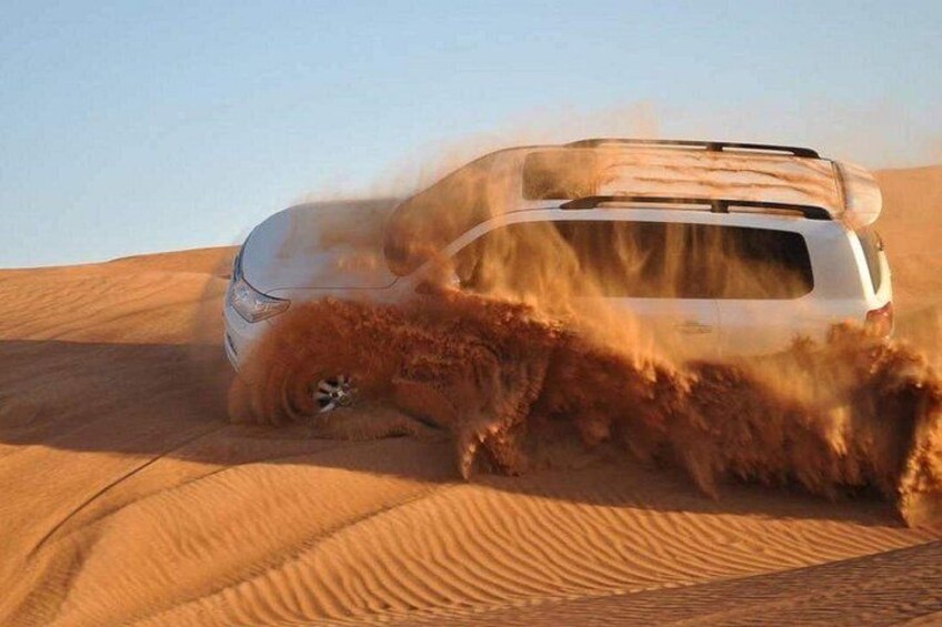 Un vehículo circulando por un desierto, levantando arena con sus neumáticos. 1